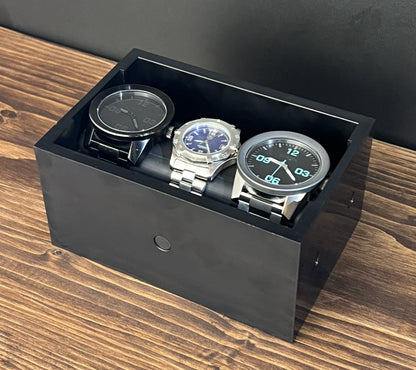 Black Cowan Cases watch, bracelet and necklace case with slide-out bar, holding three watches upright
