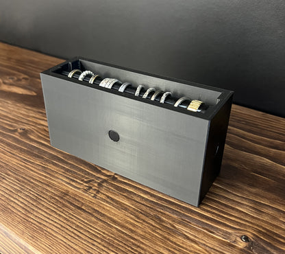 Black Cowan Cases ring case with slide-out ring bar filled with rings, side view showing the magnetic button