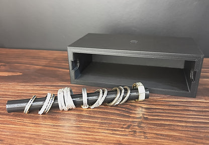 Black Cowan Cases ring case with slide-out ring bar removed and laid in front, holding rings, next to the empty case