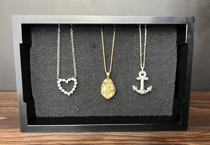 Black Cowan Cases earring, pendant, ring and cufflink case used as a necklace display, holding three necklaces